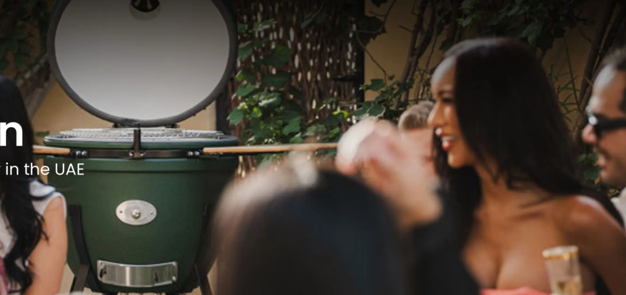 Friends gathered in the evening around an open green kamado
