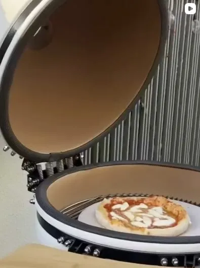 A pizza baking on the stone inside an open kamado
